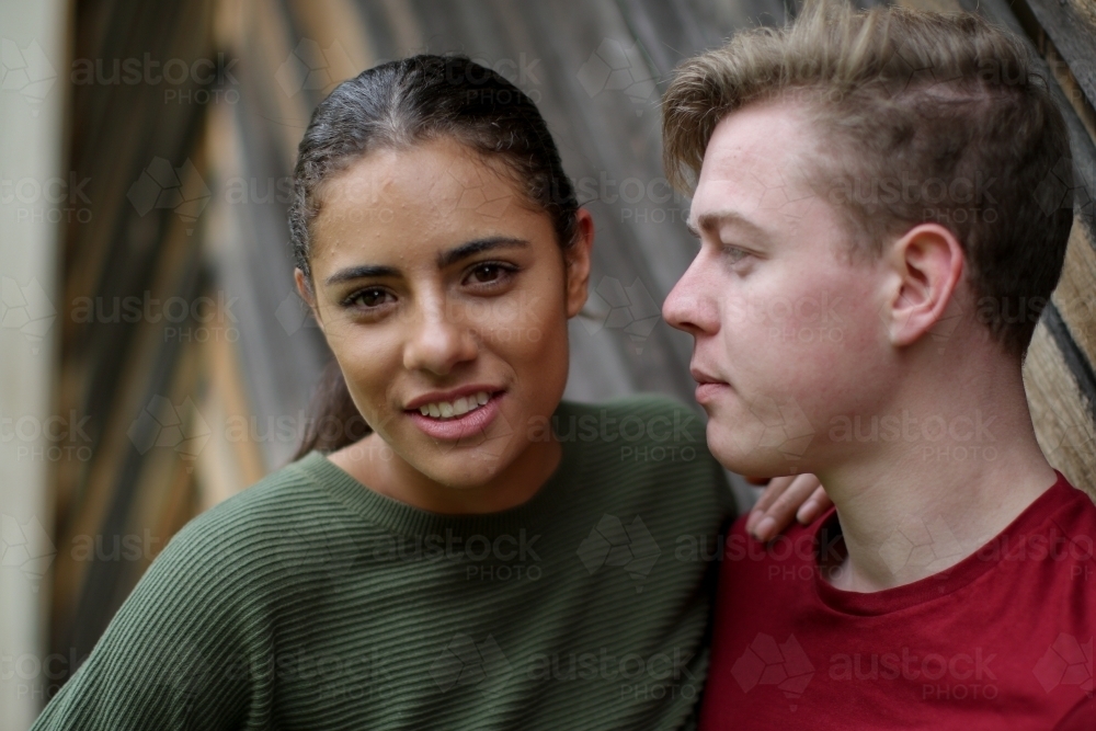 Young Fijian woman leaning on caucasian male partner and looking at camera - Australian Stock Image