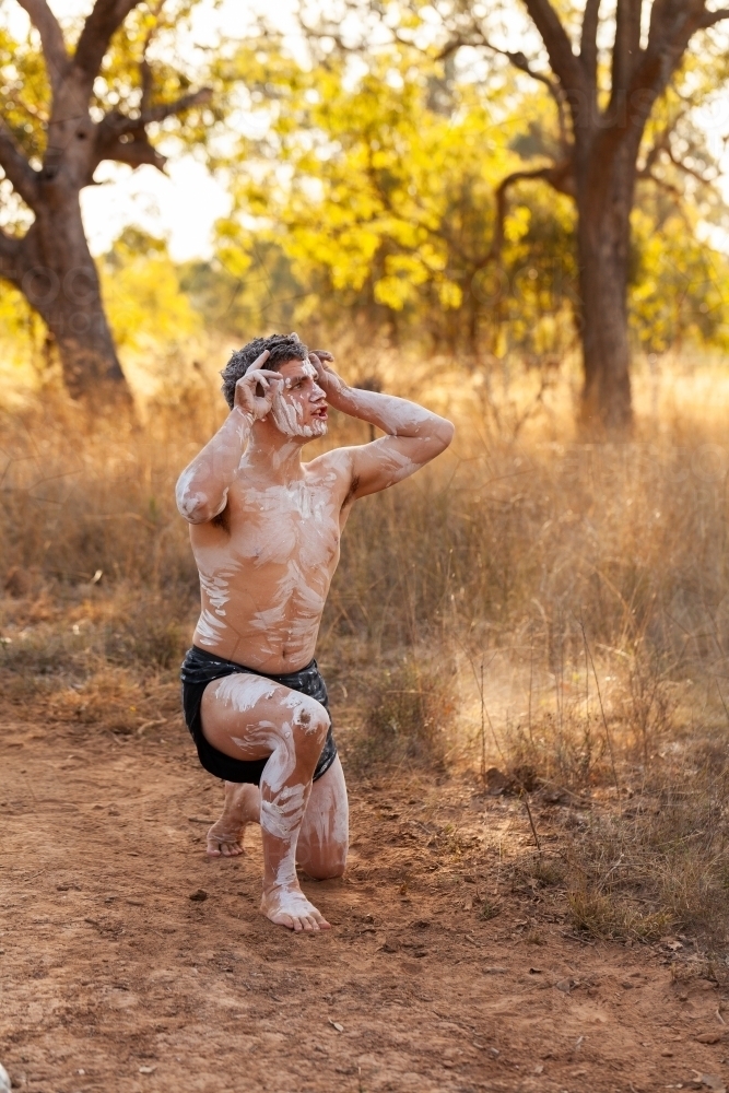 Young first nations Australian man performing aboriginals dance about kangaroos on country - Australian Stock Image