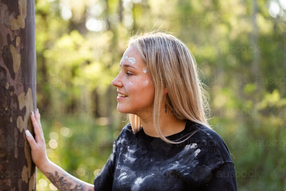 Young First Nations Australian woman side profile with cultural ochre paint on face - Australian Stock Image