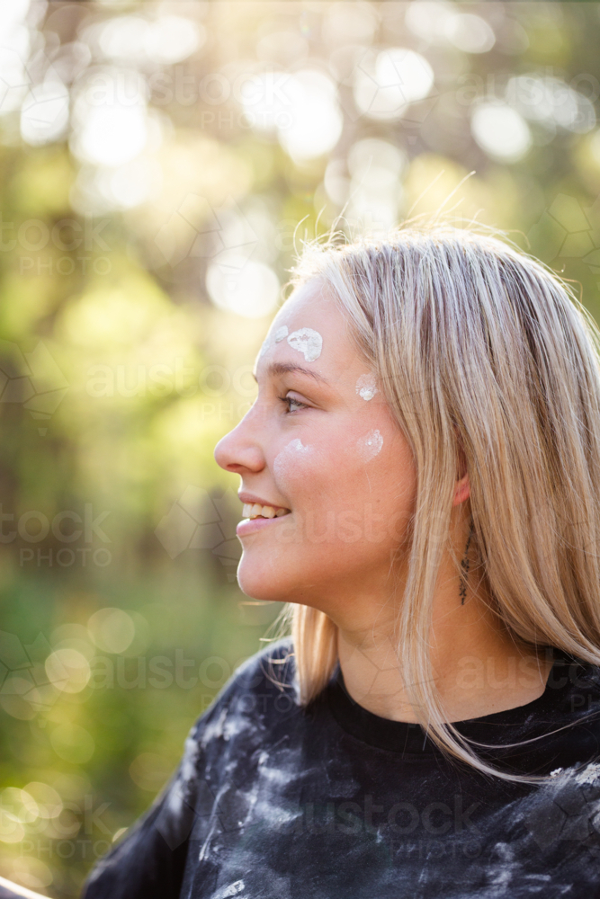 Young First Nations Australian woman side profile with cultural ochre paint on face - Australian Stock Image