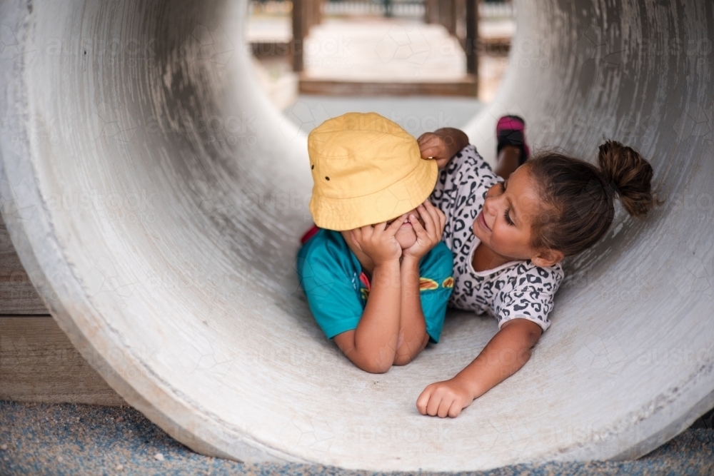 Young First Nations girl and boy playing together in a tunnel - Australian Stock Image