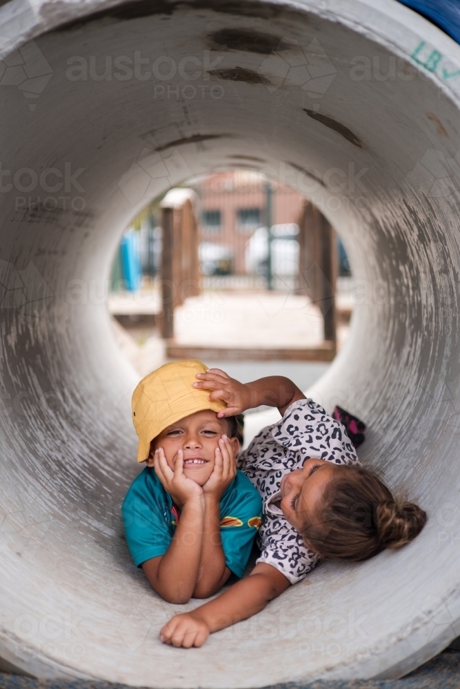 Young First Nations girl and boy playing together in a tunnel - Australian Stock Image