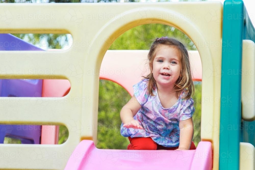 Young girl about to go down a slide on a play castle - Australian Stock Image