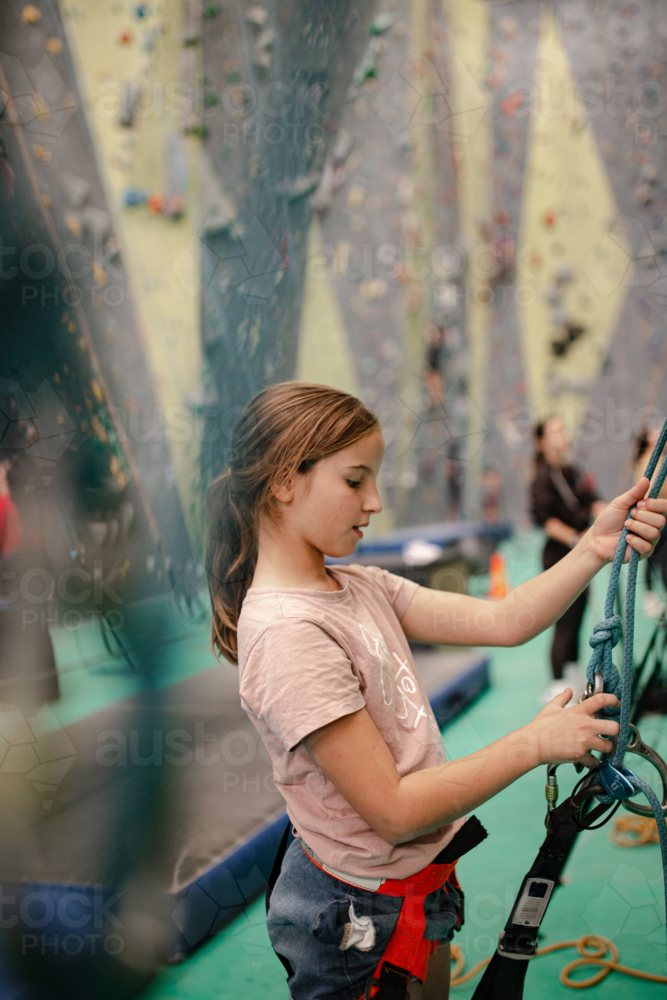 Young girl adjusting rope for rock climbing - Australian Stock Image