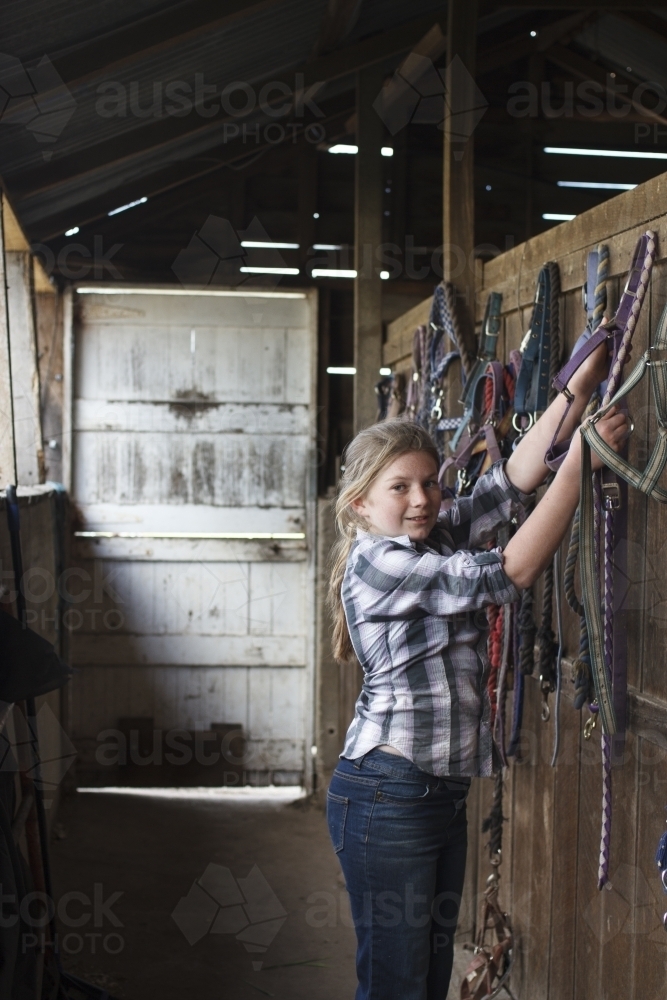 Young girl at horse riding farm in tack shed - Australian Stock Image