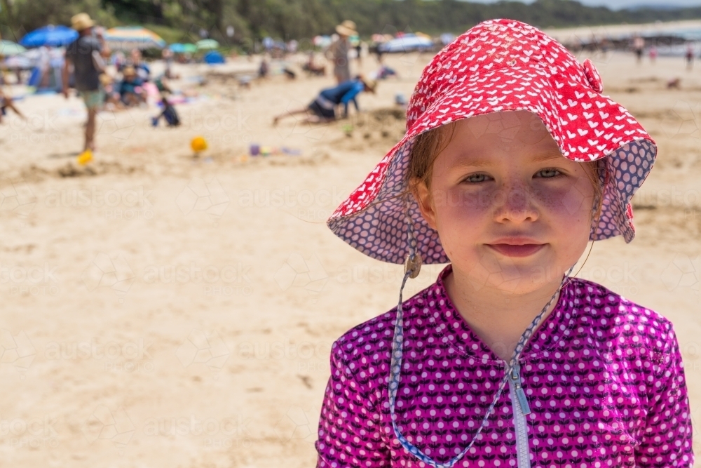 Young girl at the beach wearing a hat and rashie - Australian Stock Image
