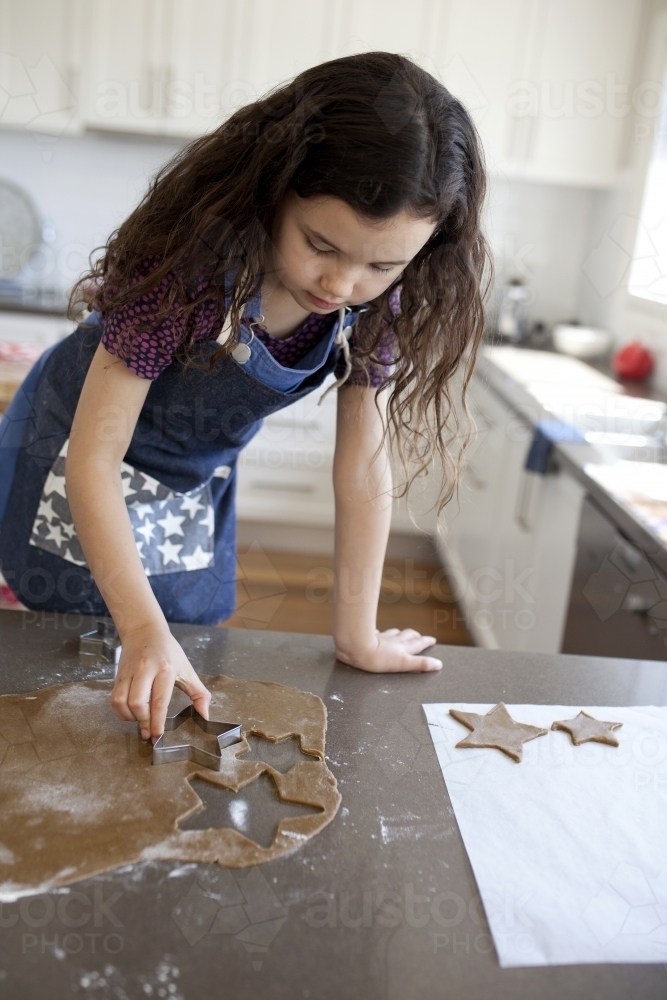 Young girl baking gingerbread cookies in kitchen - Australian Stock Image