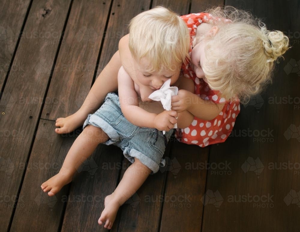Young girl blowing baby brother's nose - Australian Stock Image