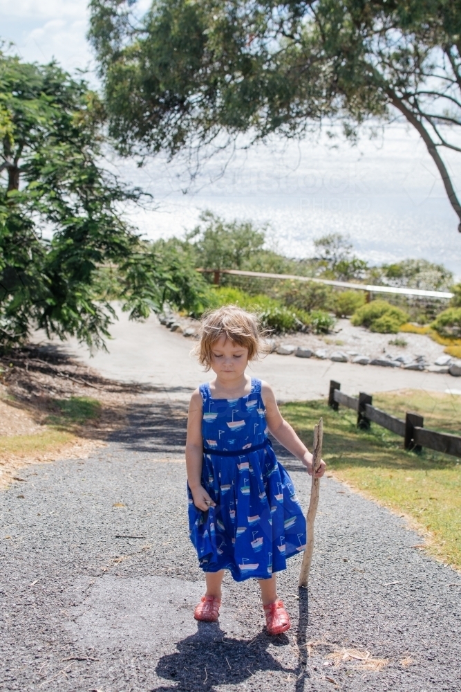 Young girl carrying her driftwood up a path - Australian Stock Image
