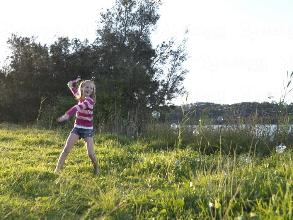 Young girl chasing bubbles outside - Australian Stock Image