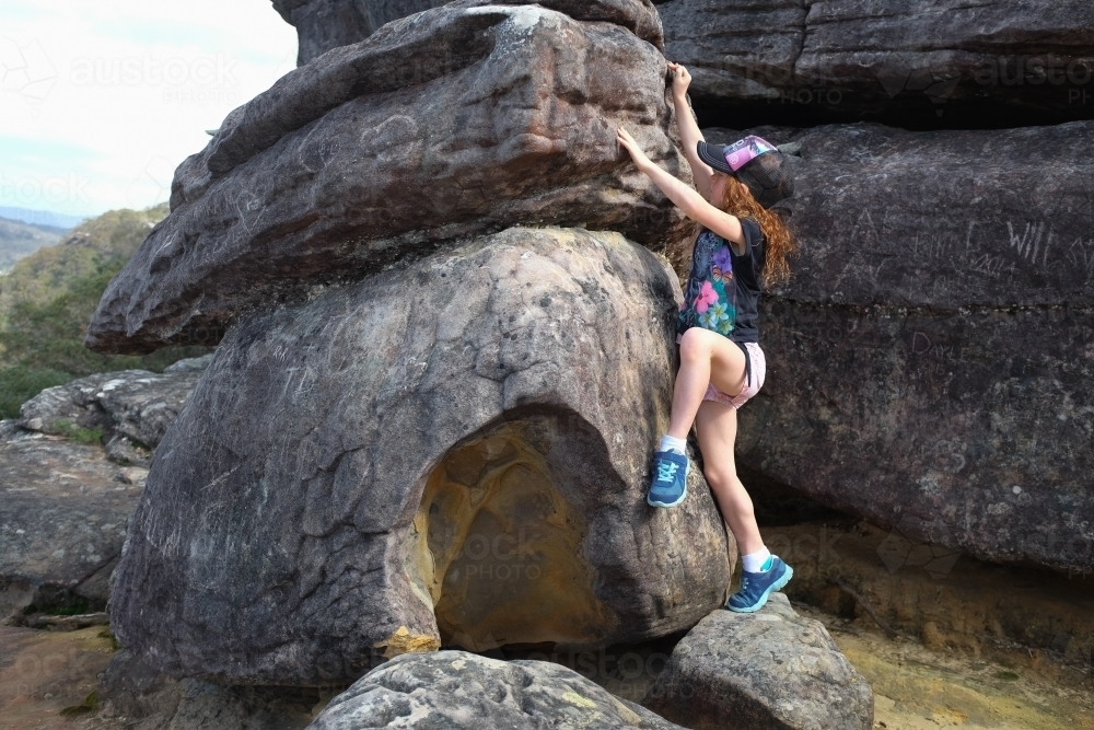 Young girl climbing a rock - Australian Stock Image