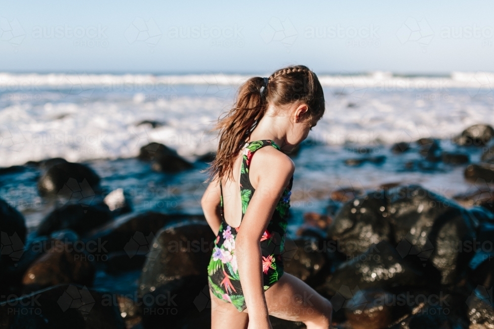 Young girl climbing rocks at the beach - Australian Stock Image