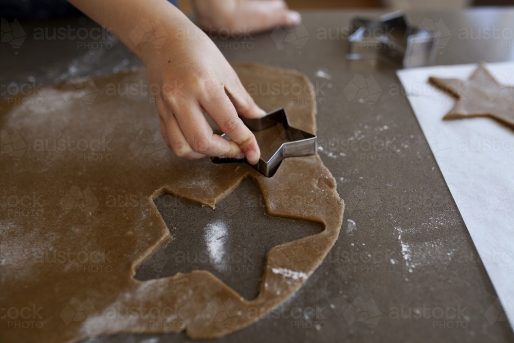 Young girl cutting shapes for gingerbread biscuits - Australian Stock Image