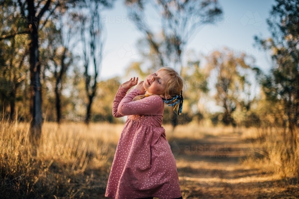 Young girl dancing outside in bushland - Australian Stock Image