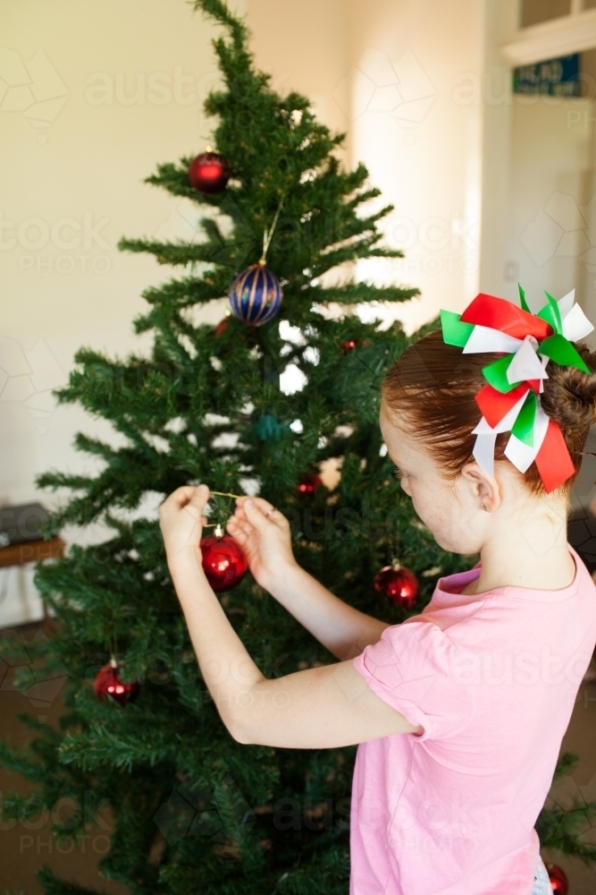 Young girl decorating a Christmas tree - Australian Stock Image