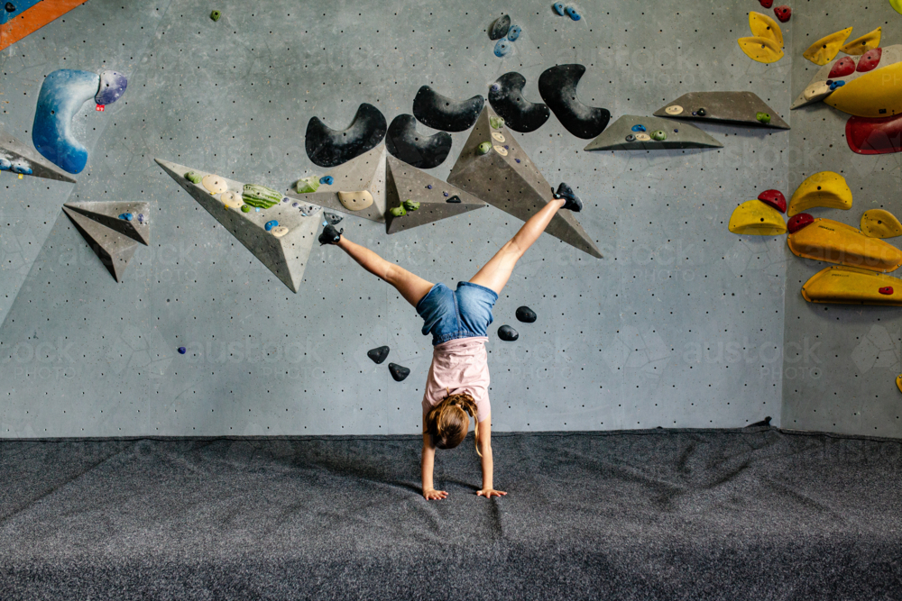 Young girl doing cartwheel in an indoor rock-climbing gym. - Australian Stock Image