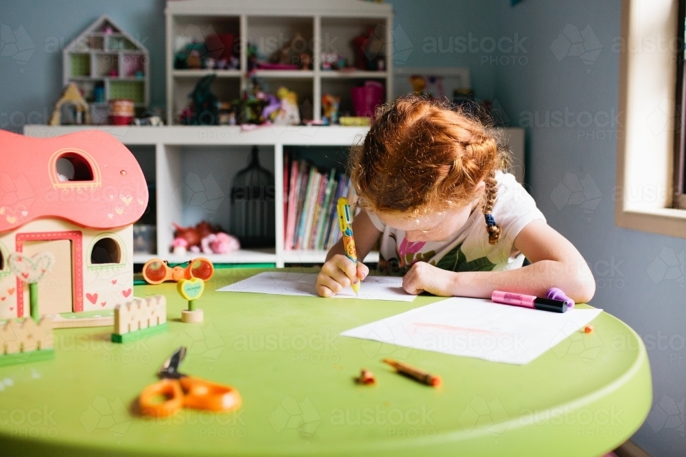 Young girl drawing at a table in a bedroom - Australian Stock Image