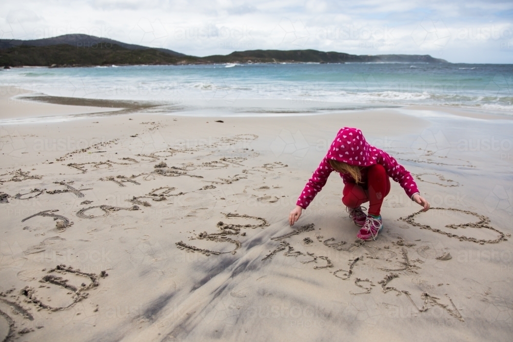 young girl drawing in the sand - Australian Stock Image