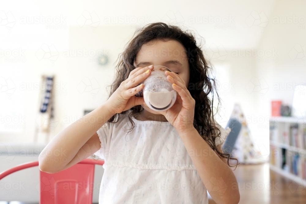 Young girl drinking chocolate milk - Australian Stock Image
