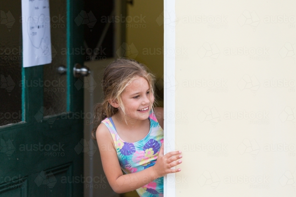 Young girl excitedly looking out of doorway - Australian Stock Image