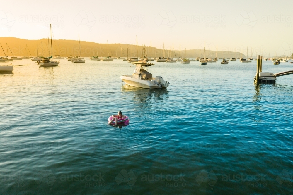 young girl floating in ocean on ring - Australian Stock Image