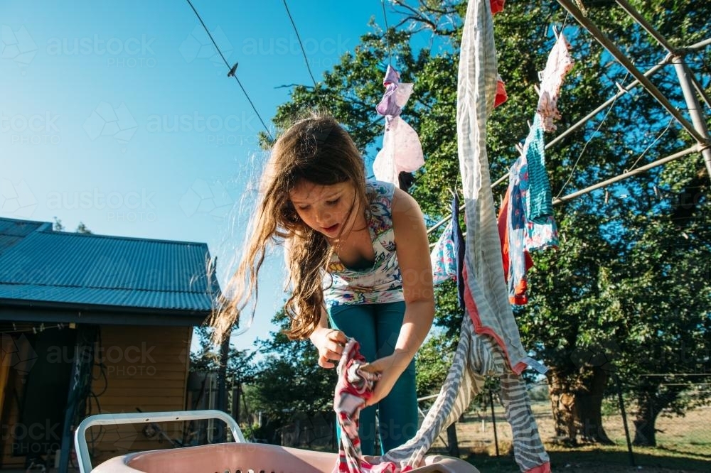 Young girl hanging out the washing - Australian Stock Image