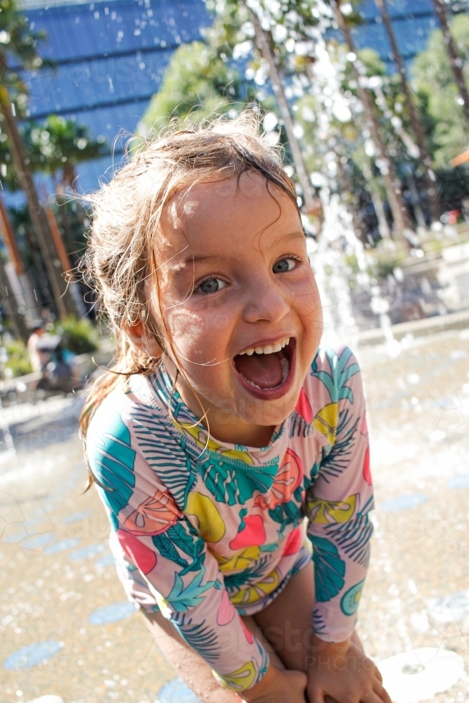 Young girl happily playing in an outdoor water park - Australian Stock Image