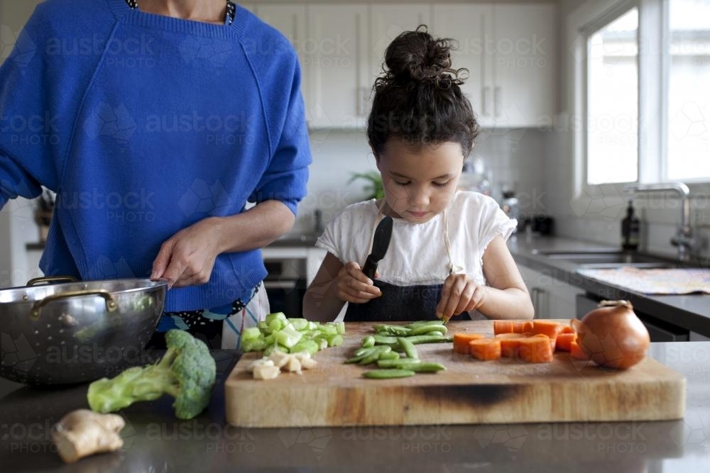 Young girl helping chop vegetables - Australian Stock Image