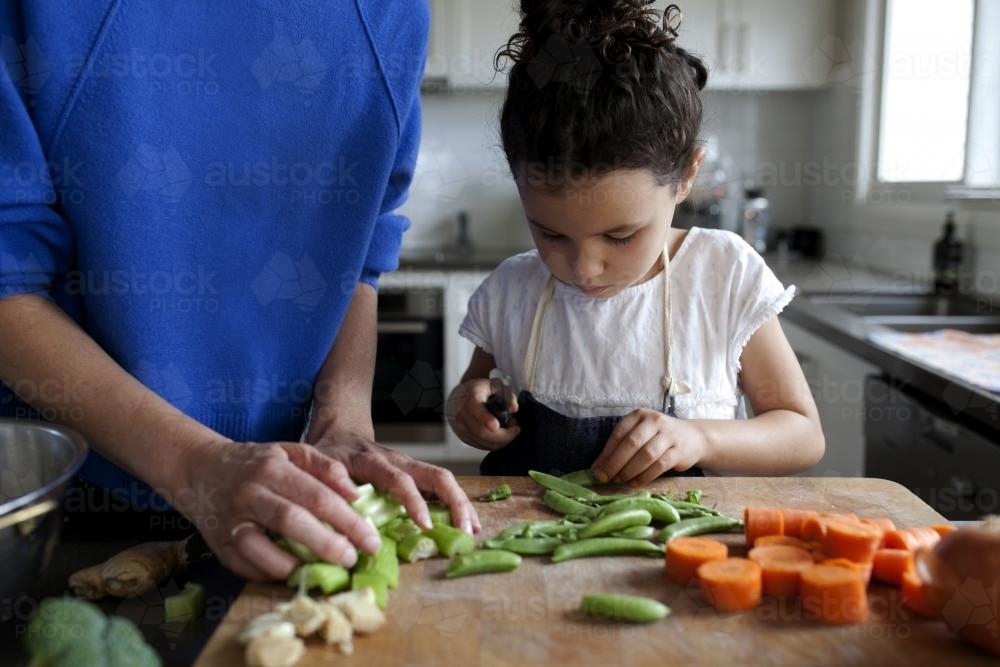 Young girl helping to chop vegetables - Australian Stock Image