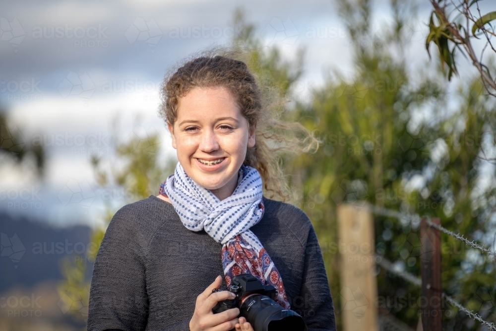 Young girl holding a camera smiling at the camera - Australian Stock Image