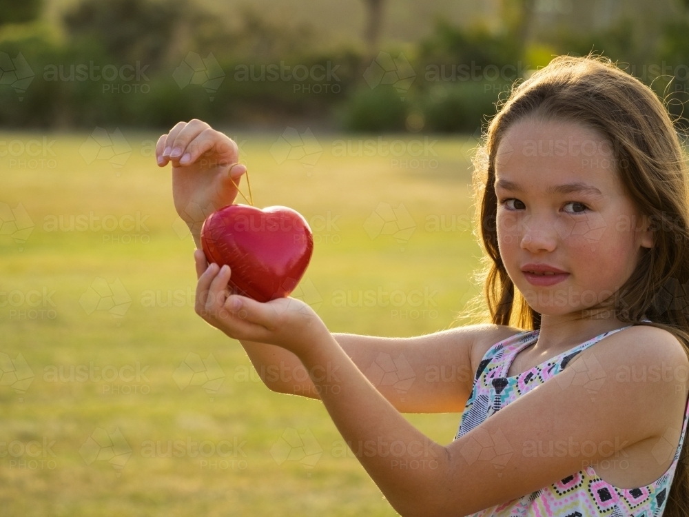 Young girl holding a red love heart. Be my Valentine - Australian Stock Image