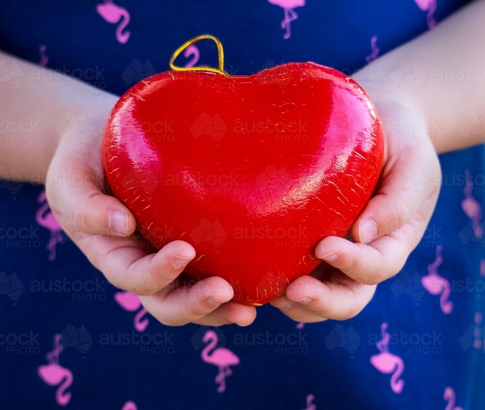 Young girl holding a red love heart in her hands Valentine - Australian Stock Image