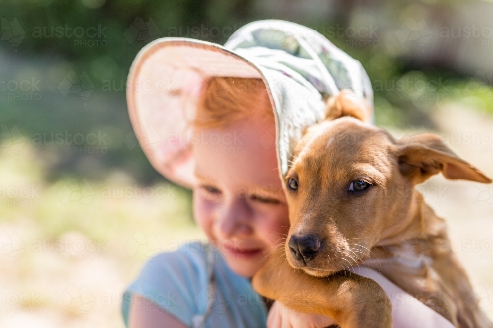 Young girl holding a tan kelpie puppy - Australian Stock Image
