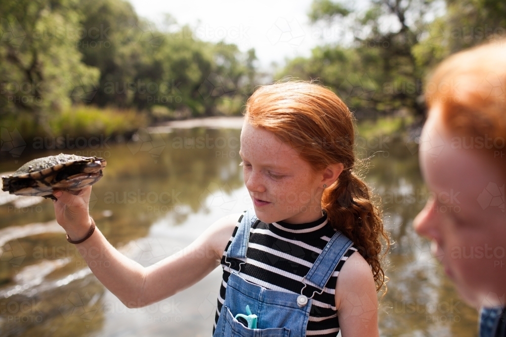 Young girl holding a turtle by the river - Australian Stock Image