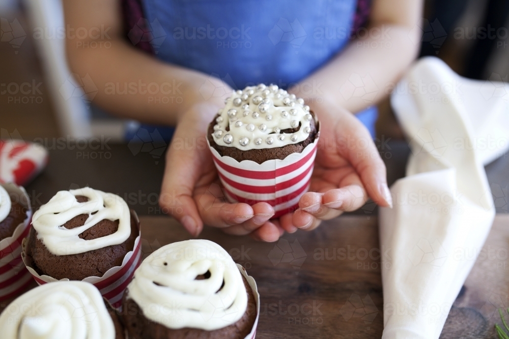 Young girl holding decorated cupcake in her hands - Australian Stock Image