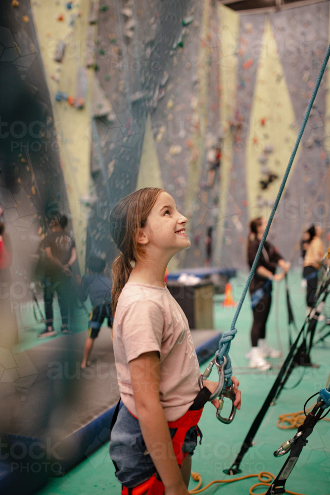 Young girl holding rope for rock climbing while looking up - Australian Stock Image