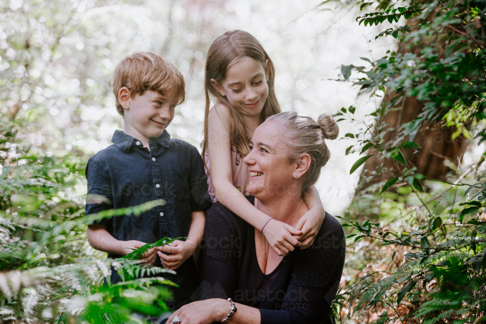 Young girl hugging mum from back in bushland - Australian Stock Image