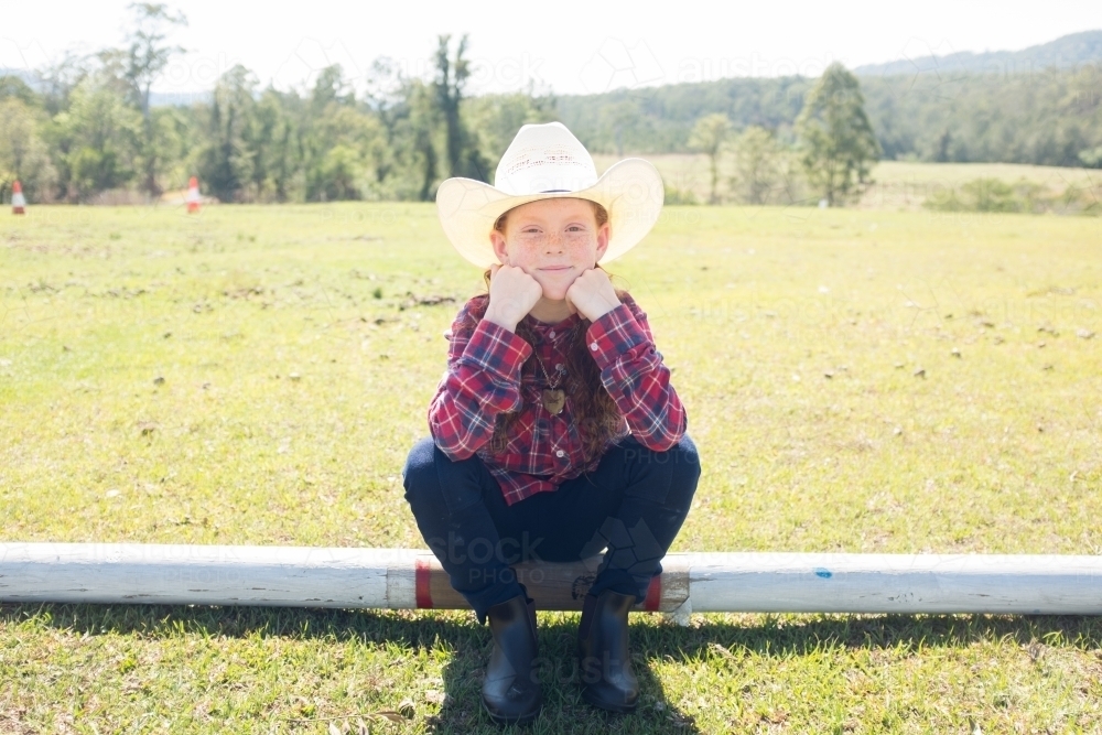 Young girl in a cowboy hat sitting on a log - Australian Stock Image