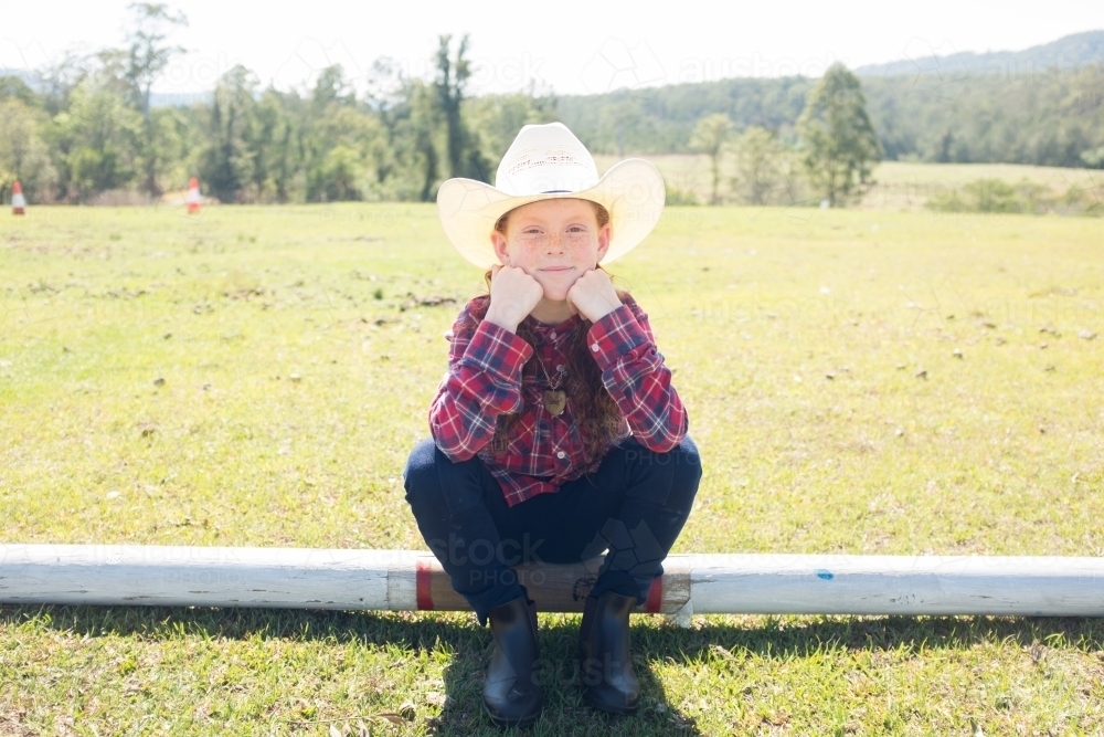 Young girl in a cowboy hat sitting on a log - Australian Stock Image