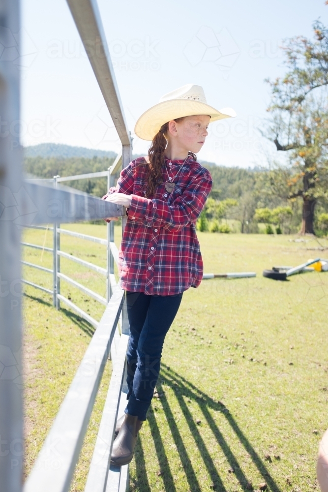 Young girl in a cowboy hat standing on a fence - Australian Stock Image