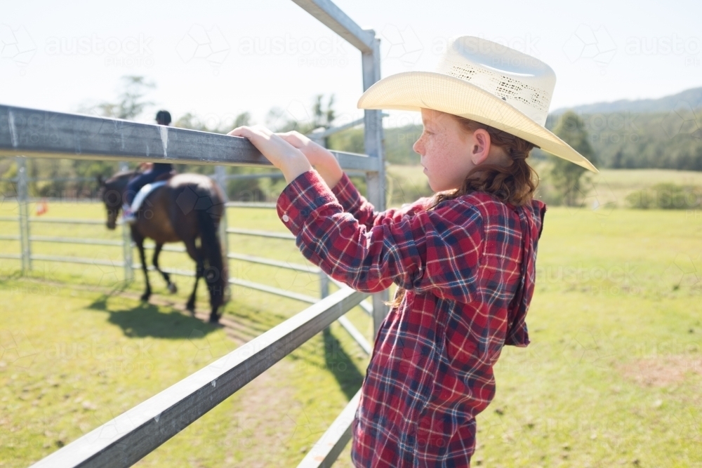 Young girl in a cowboy hat watching a horse being ridden - Australian Stock Image