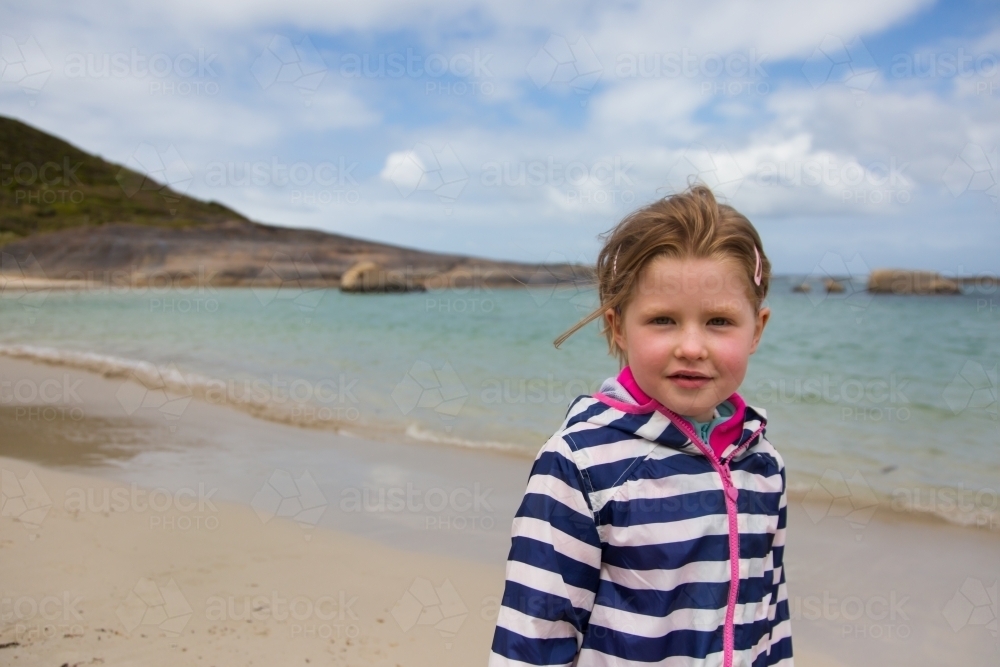 young girl in a raincoat at a beach in Spring - Australian Stock Image