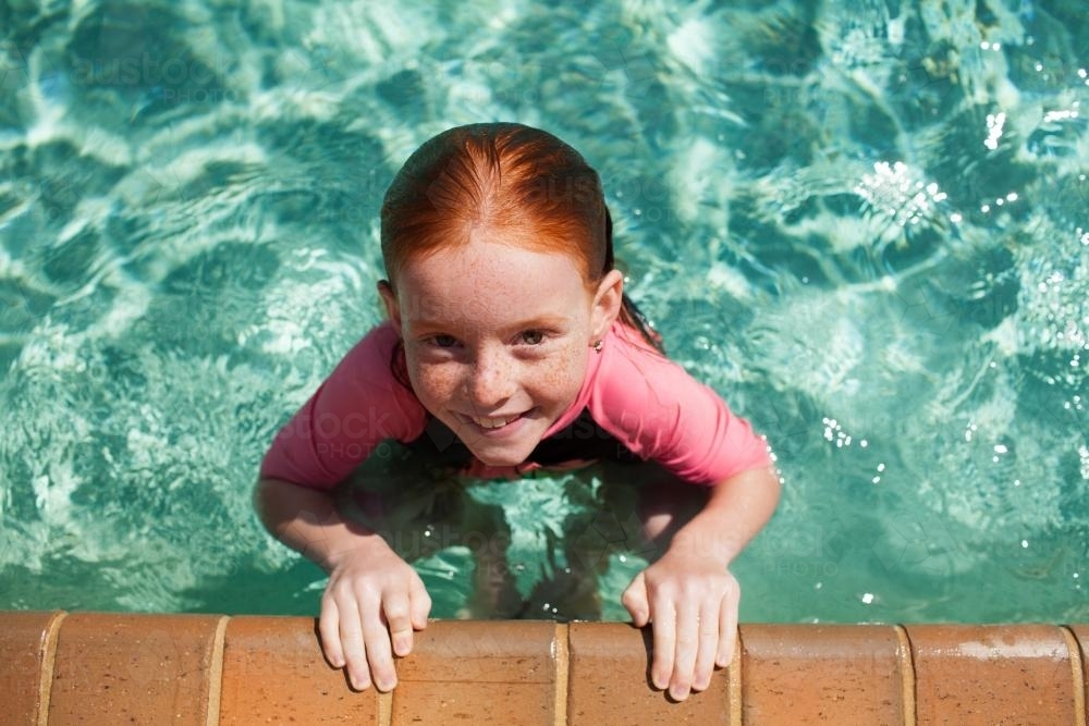 Young girl in a swimming pool looking up - Australian Stock Image