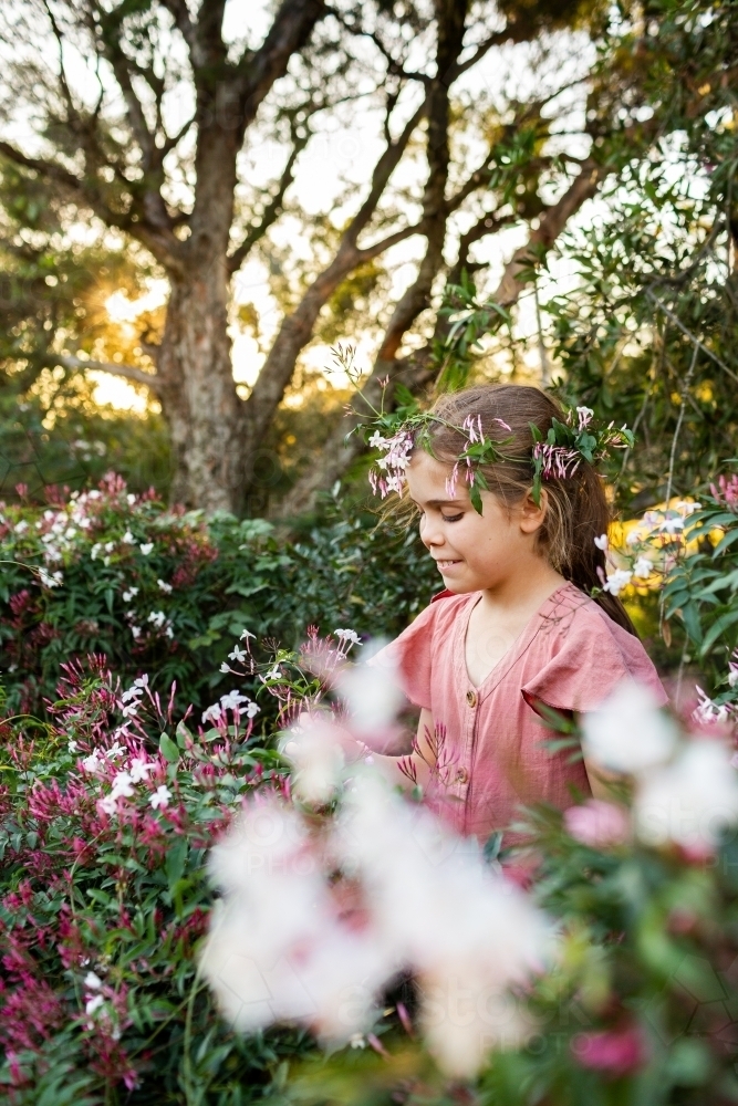 Young girl in garden with white jasmine flower crown at sunset - Australian Stock Image