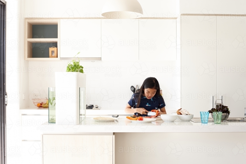 Young girl in kitchen cooking - Australian Stock Image