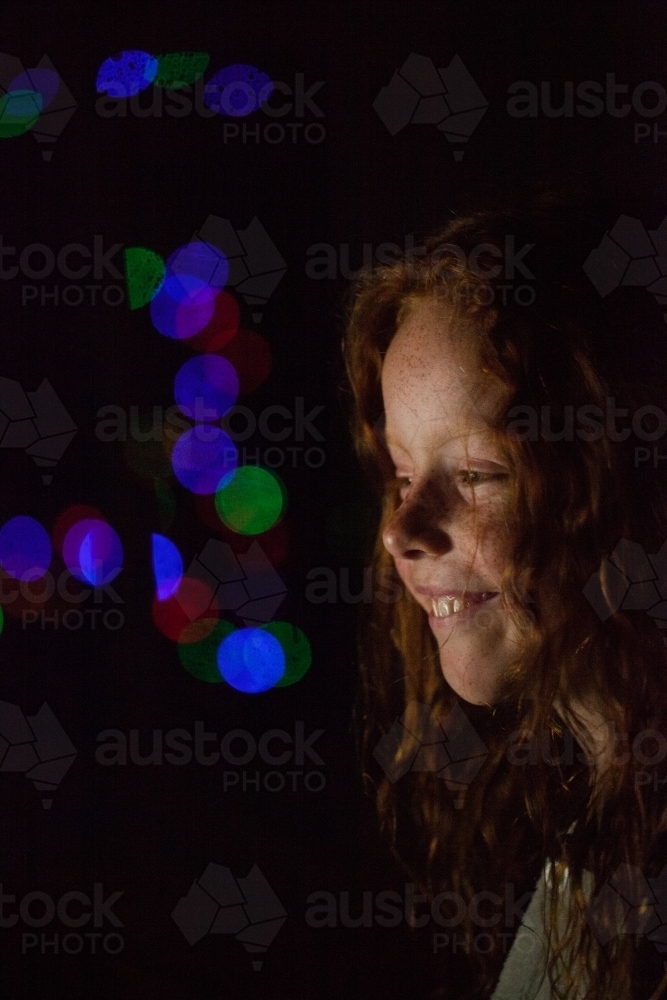 Young girl in low light with coloured lights - Australian Stock Image