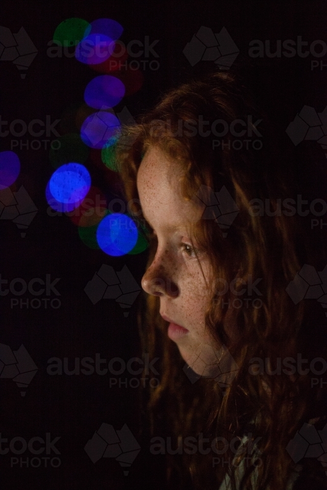 Young girl in low light with coloured lights - Australian Stock Image