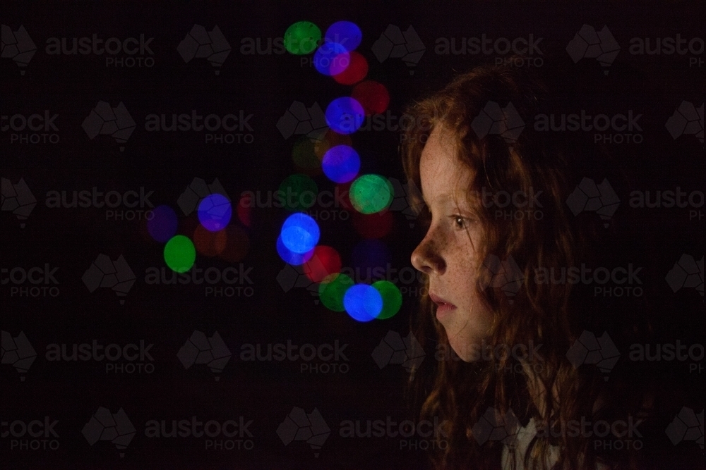 Young girl in low light with coloured lights - Australian Stock Image