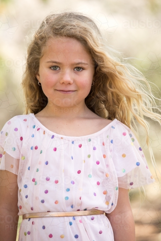 Young girl in polka-dot dress with hair blowing in the wind - Australian Stock Image