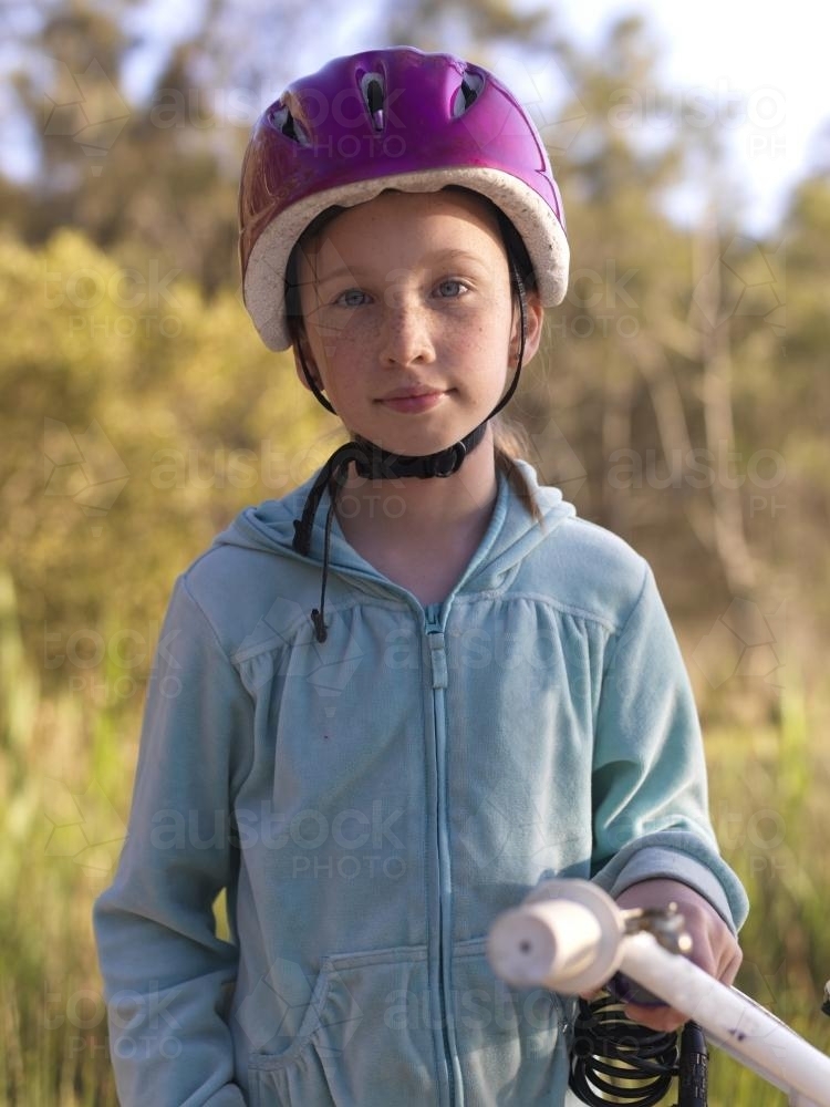 Young girl in purple helmet preparing to go bike riding - Australian Stock Image